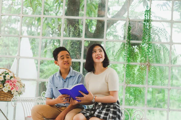 Kız ve erkek kardeş bir saksıda kitap okuyorlar.