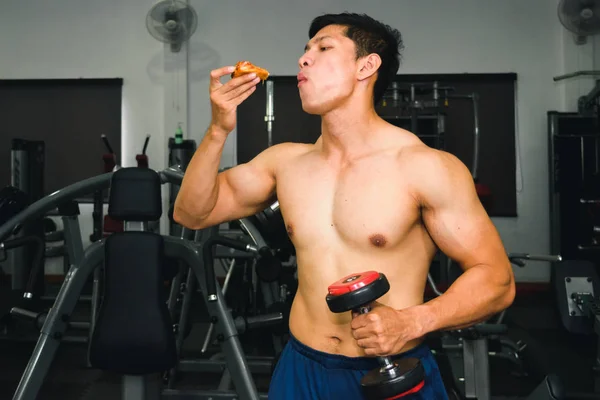 Ásia homem tem muscular comer pizza e levantamento dumbbell — Fotografia de Stock