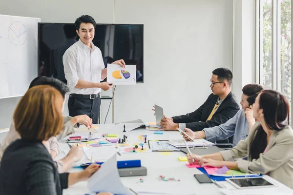 Bir grup Asyalı iş adamı tartışıyorlar. Çalışanlar ön plandadır.