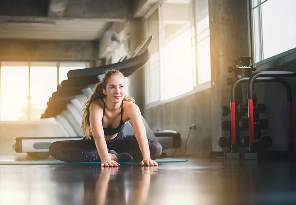 Schöne Athletin zog einen Sportanzug an. Dehnen eines Muskels auf einem — Stockfoto