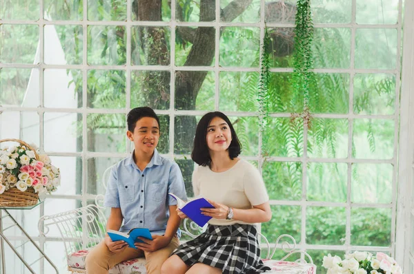 Kız ve erkek kardeş bir saksıda kitap okuyorlar.