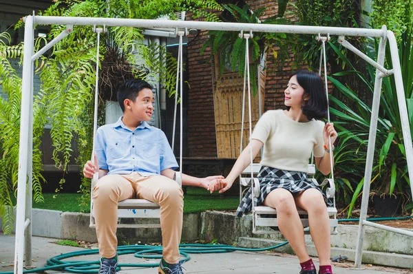 Kız ve erkek kardeş evin bahçesinde salıncak oynuyorlar.