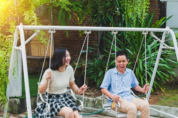 Kız ve erkek kardeş evin bahçesinde salıncak oynuyorlar.