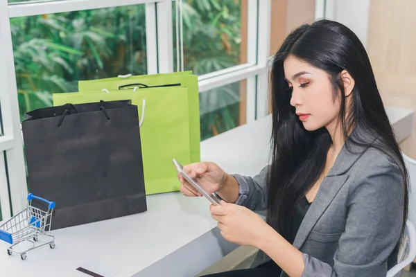 アジアの女の子オンラインショッピングに座っている。電話とクレジットカードで。ハ — ストック写真