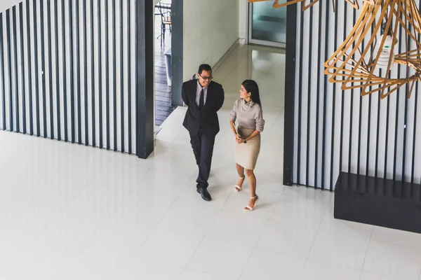 Yöneticiler ve sekreterler kapalı koridorlarda yürüyorlar.