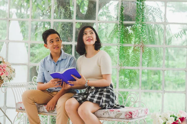 Kız ve erkek kardeş bir saksıda kitap okuyorlar.