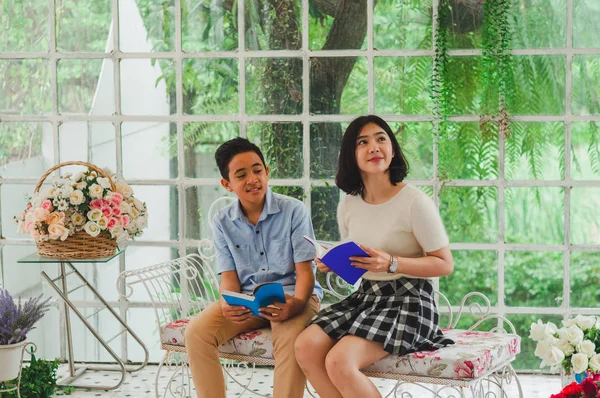 Kız ve erkek kardeş bir saksıda kitap okuyorlar.