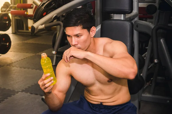 Asijský muž má svalové cvičení v tělocvičně a je unavený, takže Dr. — Stock fotografie