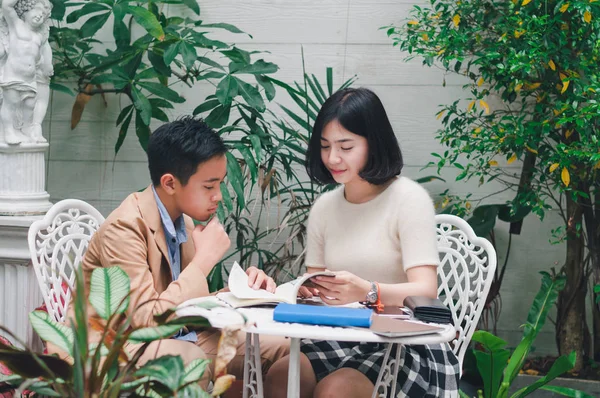 Kız kardeşi evin bahçesinde erkek kardeşine öğretiyor.