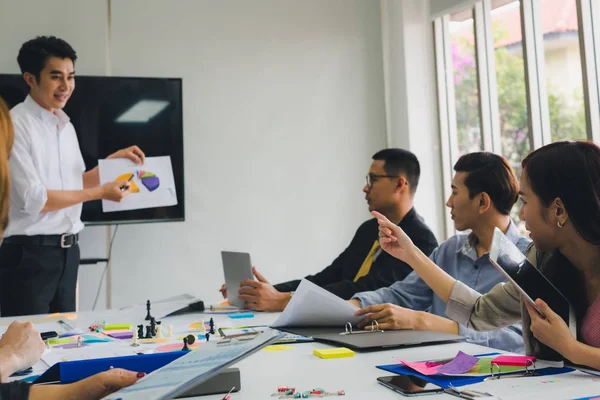 Bir grup Asyalı iş adamı tartışıyorlar. Çalışanlar ön plandadır.