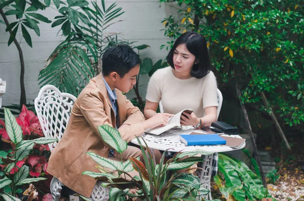 Kız kardeşi evin bahçesinde erkek kardeşine öğretiyor.