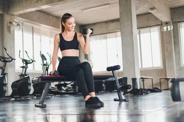 Güzel beyaz kız, halteri kaldırarak egzersiz yapıyor. 