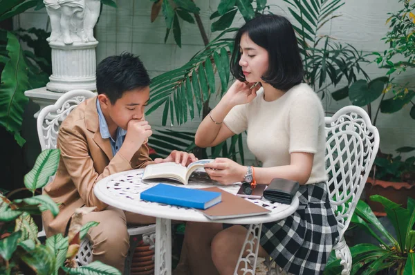 Kız kardeşi evin bahçesinde erkek kardeşine öğretiyor.