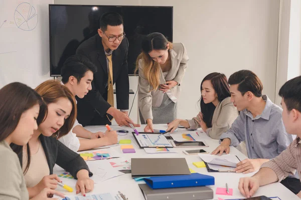 Ryhmä aasialaisia liikemiehiä keskustelee työstään. — kuvapankkivalokuva