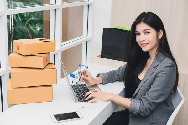 İnternetten alışveriş yapan Asyalı bir kızın portresi. Telefonla ve parayla.