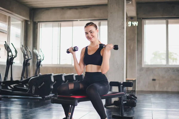 Beautiful girl caucasian is exercising with lifting dumbbell in — Stock Photo, Image