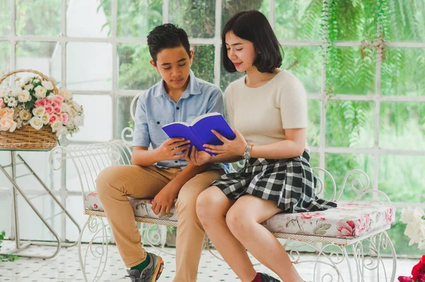 Kız ve erkek kardeş bir saksıda kitap okuyorlar.