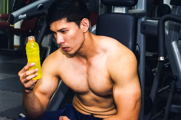 Asyalı adamın spor salonunda kas egzersizi var ve çok yorgun.