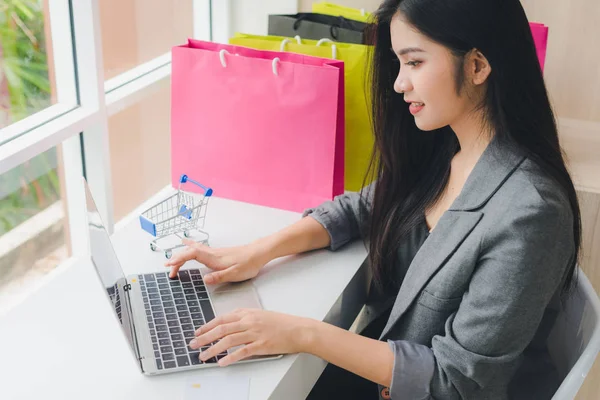 Asyalı kız internette alışveriş yapıyor. Telefon ve kredi kartıyla. Ne?