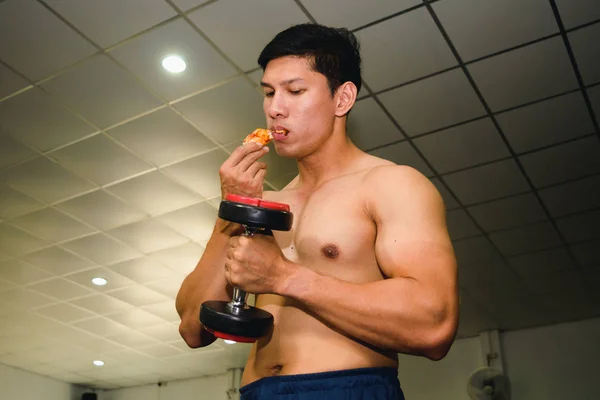 アジアの男は筋肉を持っています食べるピザと持ち上げるダンベル — ストック写真