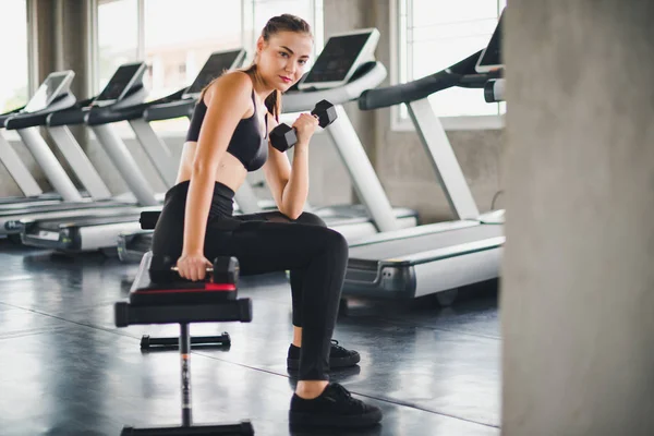 Güzel beyaz kız, halteri kaldırarak egzersiz yapıyor. 