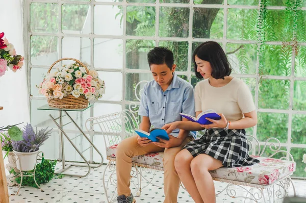 Kız ve erkek kardeş bir saksıda kitap okuyorlar.