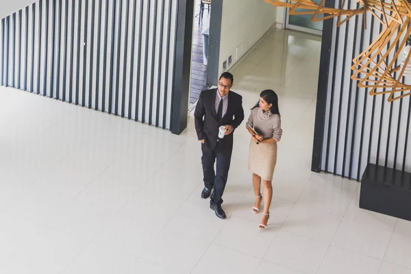 Yöneticiler ve sekreterler kapalı koridorlarda yürüyorlar.