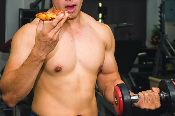 Asian man has muscle Eating pizza and lifting dumbbell — Stock Photo, Image