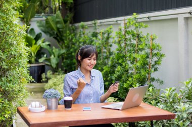 Asyalı kadınlar defter çalar ve bahçede müzik dinlerler..