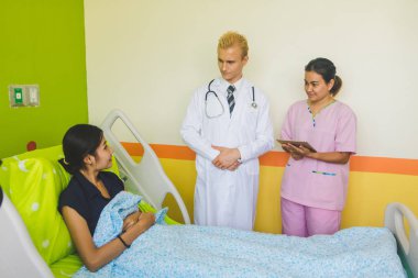 Doktor ve hemşire sethoscop kullanarak kalbi dinliyorlar.