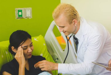 Doktor ve hemşire sethoscop kullanarak kalbi dinliyorlar.