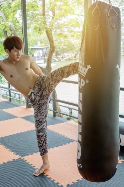 Asyalı adamlar kum torbasını tekmeliyor.