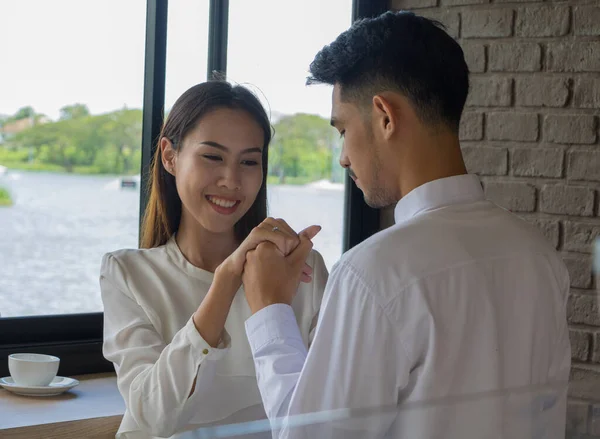 Asian young man hold a wedding ring box to get married in coffee