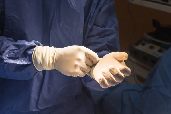 El equipo quirúrgico está usando guantes quirúrgicos a los pacientes en operatin — Foto de Stock