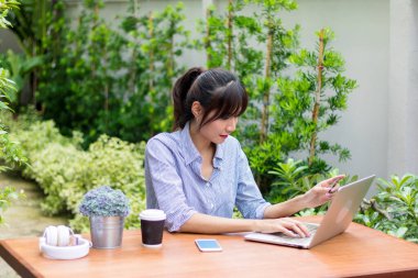 Asyalı kadınlar defter çalar ve bahçede müzik dinlerler..