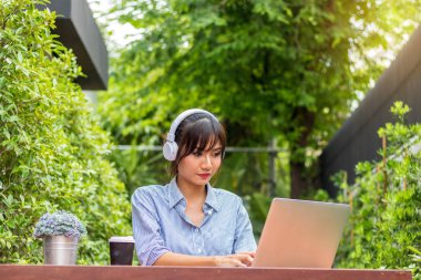Asyalı kadınlar defter çalar ve bahçede müzik dinlerler..