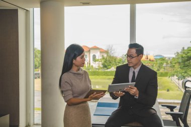 İş adamı ve sekreter ofiste iş konuşuyorlar..