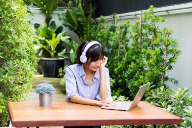 Asyalı kadınlar defter çalar ve bahçede müzik dinlerler..