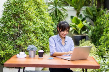 Asyalı kadınlar defter çalar ve bahçede müzik dinlerler..