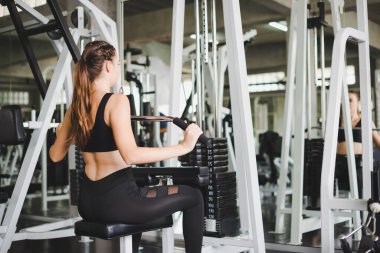 Spor salonunda kol ve omuz kaslarıyla oynamak için bir çekme makinesiyle egzersiz yapan güzel bir sporcu. Spor konsepti alıştırması.