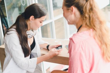 Kahve içip telefonla oynayan iki güzel genç kadın. rahatlama konsepti.