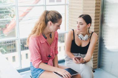 Telefon ve tablet oynayan iki güzel genç kadın. rahatlama konsepti.