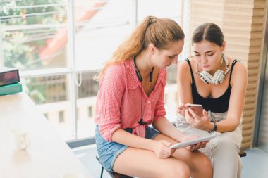 Telefon ve tablet oynayan iki güzel genç kadın. rahatlama konsepti.