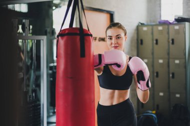 Güzel fitness boks salonu. Pembe bir boks eldiveni giyiyor ve egzersiz yapıyor. Kum torbası bir çift yumruktur..