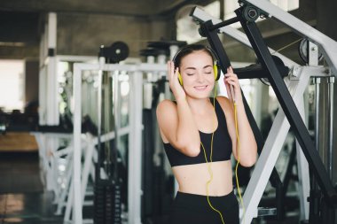 Güzel kadınlar spor salonuna egzersiz yapmaya gelir ve kulaklıklardan müzik dinleyerek rahatlarlar. Spor giyer..