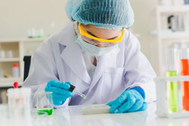 Asyalı bilim adamları laboratuvarda test ve analiz için kimyasallar hazırlıyorlar. Bilim adamları cam ve beyaz gömlekleri temizliyorlar. Bilim ve Kimya Konsepti