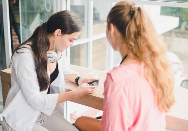 Kahve içip telefonla oynayan iki güzel genç kadın. rahatlama konsepti.