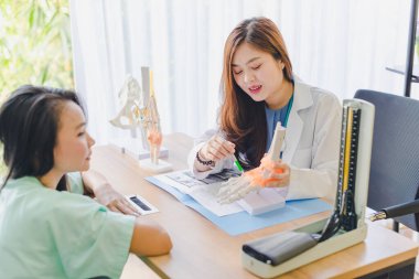 Asyalı güzel kadın doktor hastanın ayaklarındaki ağrıyı analiz eder ve açıklar..