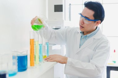 Asyalı bilim adamları laboratuvarda test ve analiz için kimyasallar hazırlıyorlar. Bilim adamları cam ve beyaz gömlekleri temizliyorlar. Bilim ve Kimya Konsepti