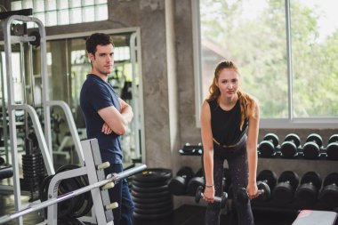 Spor eğitmeni genç bayan sporcuların eğitimini kontrol ediyor. Spor salonu konseptinde atlet fitness egzersizleri.